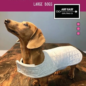 May include: A brown dachshund wearing a white quilted jacket. The image includes text that reads "The Dandy-Doo Totally Reversible, Totally Adjustable Jacket Pattern for Medium & Large Dogs" and "Quilted Jacket Pattern for Your Best Friend."