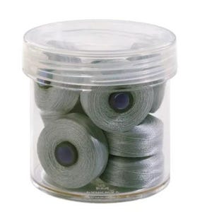 May include: A clear plastic container filled with several spools of gray thread. Each spool has a dark blue center. The container has a clear lid. The thread appears to be for sewing or crafting.