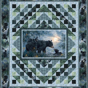 May include: A quilt with a black bear family in the center surrounded by a geometric pattern of black, green, and blue triangles and squares.