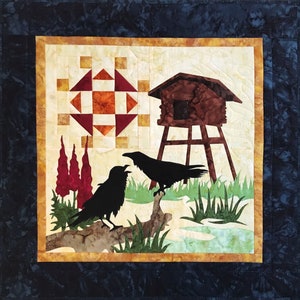 May include: A quilt block with a brown wooden birdhouse on a tall wooden stand, two black crows perched on a branch, and a red and orange geometric pattern in the background.