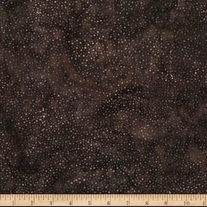 May include: A dark brown fabric featuring a dense, mottled pattern of tiny white dots scattered across the surface. A ruler is positioned along the bottom edge, showing measurements in inches from 0 to 11, indicating the scale of the textile.