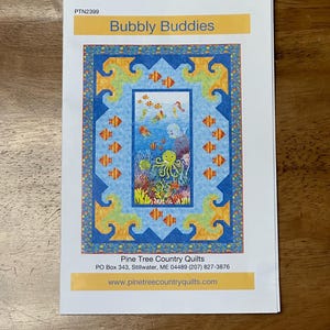 May include: A quilting pattern titled "Bubbly Buddies" featuring an underwater scene with an octopus, fish, and coral. The pattern is from Pine Tree Country Quilts, PO Box 343, Stillwater, ME 04489 (207) 827-3876, www.pinetreecountryquilts.com.