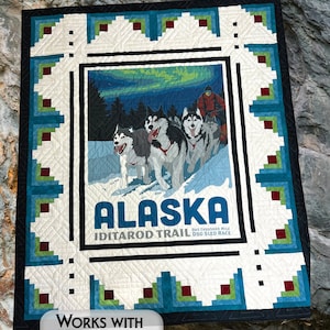 May include: A quilt pattern featuring a vintage poster of a dog sled race in Alaska. The poster is surrounded by a blue, green, and red border. The text on the poster reads "ALASKA IDITAROD TRAIL ONE THOUSAND MILE DOG SLED RACE". The quilt pattern is designed to work with 1 yard panels.