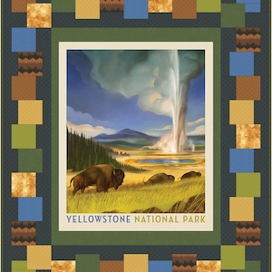 May include: A quilt featuring a central image of Yellowstone National Park with bison and a geyser. The image is framed by a border of green, blue, brown, and gold squares on a dark gray background. The text "YELLOWSTONE NATIONAL PARK" is visible.