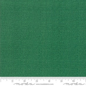 May include: A close-up of a green fabric with a subtle textured pattern. The fabric has a slightly rough, almost linen-like feel.