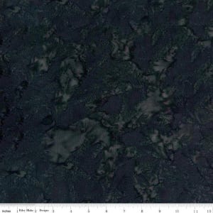 May include: Dark blue and green fabric with a mottled, batik-like pattern. The fabric has a textured appearance with areas of lighter green and darker blue, creating a marbled effect. The image includes a ruler along the bottom edge.