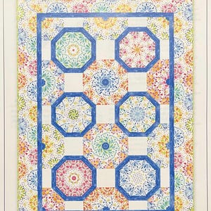 May include: A quilt pattern featuring a kaleidoscope design with blue, green, yellow, orange, and pink colors. The quilt is made up of octagons and squares. The title "Summer Breeze Kaleidoscope Quilt" is at the top of the image.