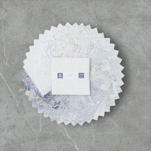 May include: A collection of white and blue fabric squares arranged in a circular pattern. The squares feature various floral and abstract designs. A central square displays the text "Cotton Ball" and two small labels.