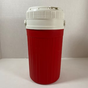 May include: A red and white insulated drinks container with a white lid and a handle on each side. The container has a ribbed design.