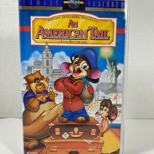 May include: A VHS tape case featuring the animated film "An American Tail" with a blue background and a cartoon mouse character holding a suitcase. The title "An American Tail" is in white text with a red outline. The text "A Don Bluth Film" is in white text below the title. The text "Steven Spielberg Presents" is in white text above the title.
