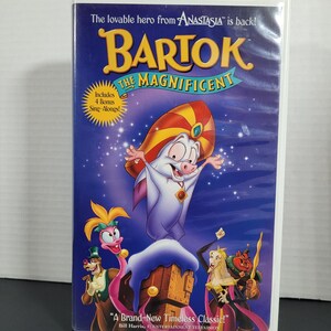 Peut inclure: Une jaquette de cassette VHS pour le film d'animation "Bartok le Magnifique". La jaquette présente une image de dessin animé de Bartok, une petite créature blanche ressemblant à une chauve-souris avec un turban rouge et jaune, sur un fond de ciel nocturne bleu étoilé. Le texte "A Brand-New Timeless Classic!" est imprimé en bas de la jaquette.