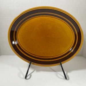 May include: A brown oval ceramic serving platter with two dark brown bands around the rim.