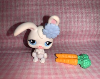 Pode incluir: Brinquedo de coelho branco com uma flor azul na cabeça e um brinquedo de cenoura verde e laranja.