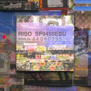 May include: A square print featuring the text "RISO SF9450EIIU SERIAL No. 44060355" in black and white. The print has a floral and abstract design with a purple and blue color scheme. The print is surrounded by other prints.
