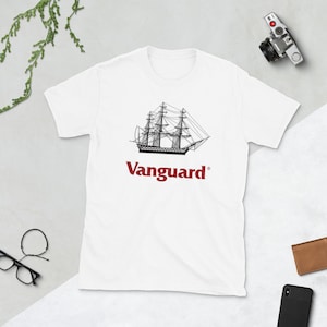 Könnte beinhalten: Weißes T-Shirt mit einer schwarzen Strichzeichnung eines Segelschiffs mit drei Masten. Darunter steht in Rot das Wort "Vanguard". Das T-Shirt besteht aus einem weichen Material.