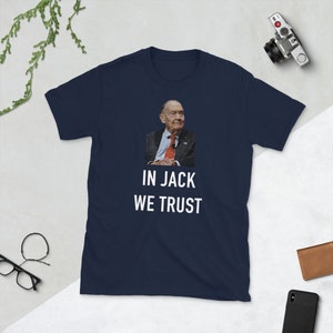 May include: Navy blue t-shirt featuring a portrait of a man in a suit and tie. The text "IN JACK WE TRUST" is printed in white below the image. The shirt is a short-sleeved crew neck.