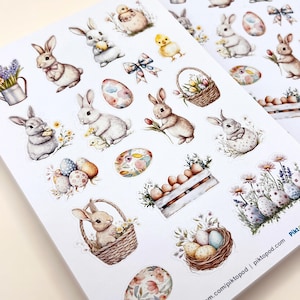 May include: Sheets of Easter-themed stickers with watercolour illustrations. The stickers show bunnies, eggs, chicks, baskets of flowers, and bows in soft pastel colours. The stickers are on a white background.