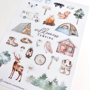 May include: A set of watercolor stickers featuring camping and wilderness themes. The stickers include a camper van, a tent, a cabin, a campfire, a squirrel, a deer, an owl, a lantern, an axe, a backpack, a mushroom, a rope, a tree, a daisy, and a wooden log. The stickers are perfect for adding a touch of nature to your planner, journal, or scrapbook.