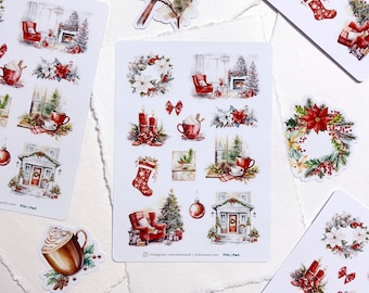 Puede incluir: Una colección de pegatinas con temática navideña con ilustraciones en acuarela. Los diseños incluyen un cardenal, coronas, calcetines, interiores acogedores con chimeneas y tazas de chocolate caliente. Las pegatinas están dispuestas sobre papel blanco.