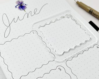 May include: A set of two clear plastic stencils with wavy edges. The stencils are designed to create decorative borders for bullet journaling. The word "June" is written in cursive at the top of the page.