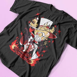 May include: Black t-shirt with a red, white, and black illustration of Lucifer Morningstar from the show "Hazbin Hotel". He is wearing a top hat and holding a red lollipop. The text "Lucifer Morningstar" is written in red and white flames.