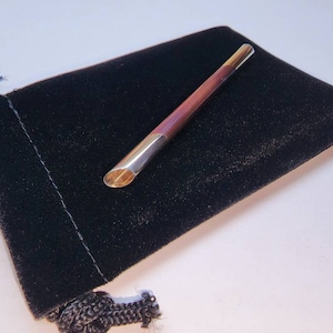 May include: A wooden and gold-toned pen with a black velvet pouch.