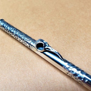 May include: A silver pipe with a hammered finish and a bird skull design at the end.