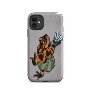 Puede incluir: Una funda de smartphone gris con una ilustración de dibujos animados de una rana negra y naranja que lleva una falda verde y sostiene un pequeño abanico azul claro. La rana tiene ojos grandes sobre un fondo gris claro sólido.