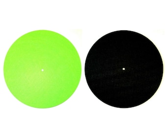 May include: Two circular turntable slipmats. One is bright green, the other is black. Each has a small hole in the center. The mats are designed to reduce friction between the record and the turntable platter.