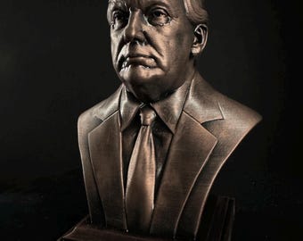 May include: A bronze bust sculpture of a man wearing a suit and tie. The bust is on a wooden base.
