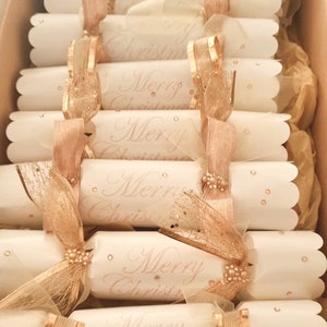 May include: A box of white and gold Christmas crackers with the text "Merry Christmas" printed on them.
