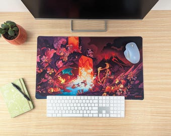 May include: A rectangular mouse pad with a colorful fantasy art design featuring a dragon, archer, and volcanic landscape. A white keyboard, light blue mouse, and a green notebook with a pen are also visible.