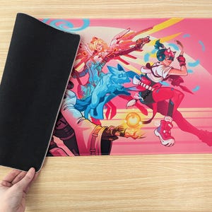 Someone is holding the mouse pad so you can see the bottom and top of it. The bottom is black rubber and has a grippy texture.