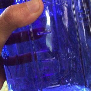 K&ouml;nnte beinhalten: Eine durchsichtige blaue Glasflasche mit einer 500 ml Messlinie. Die Flasche ist mit einer blauen Fl&uuml;ssigkeit gef&uuml;llt.
