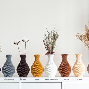 Pu&ograve; includere: Nove vasi in ceramica di diversi colori, tra cui nero, grigio argento, marrone, oro, bianco marmo, rame, nudo e legno. Ogni vaso ha un motivo a spirale unico.