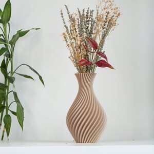 Pu&ograve; includere: Un vaso di legno marrone chiaro con un design a spirale e texture. Il vaso &egrave; pieno di fiori secchi, tra cui lavanda e foglie rosse.