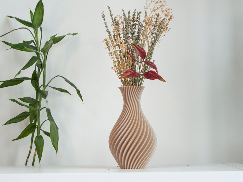Pu&ograve; includere: Un vaso di legno marrone chiaro con un design a spirale e texture. Il vaso &egrave; pieno di fiori secchi, tra cui lavanda e foglie rosse.