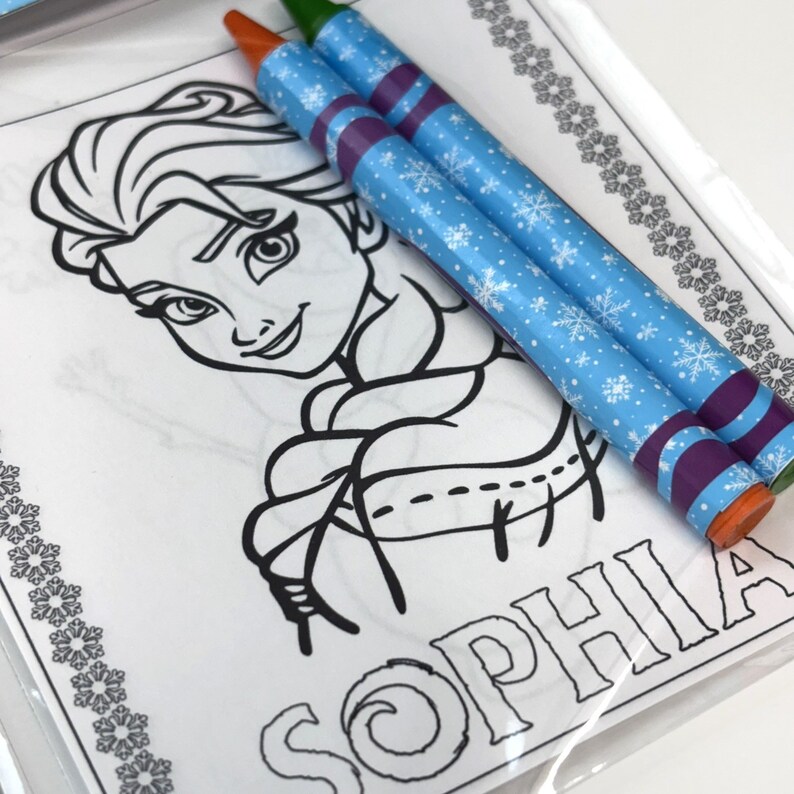 May include: A colouring page featuring a black and white line drawing of Elsa from the movie Frozen. The page includes the name "Sophia" at the bottom. Two blue and purple crayons with snowflake designs are included.