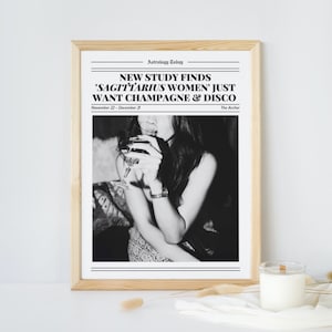 May include: Black and white newspaper style print with the headline "NEW STUDY FINDS 'SAGITTARIUS WOMEN' JUST WANT CHAMPAGNE & DISCO" and the text "November 22 - December 21 The Archer". A black and white photo of a woman holding a glass of wine is in the center of the print.