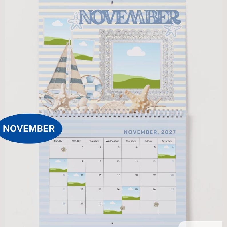 May include: A wall calendar for November 2027 featuring a nautical theme with light blue and white stripes. The top section displays the word NOVEMBER, a sailboat, a life preserver, starfish, and a decorative silver frame with landscape art.