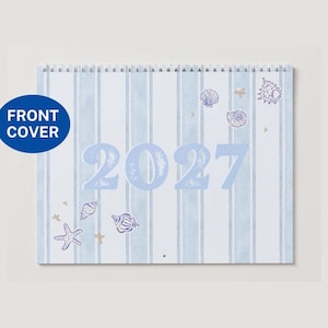 May include: A spiral-bound wall calendar with a light blue and white vertical striped background. The front cover features the year 2027 in large light blue numbers, decorated with illustrations of various seashells and starfish in blue and tan.