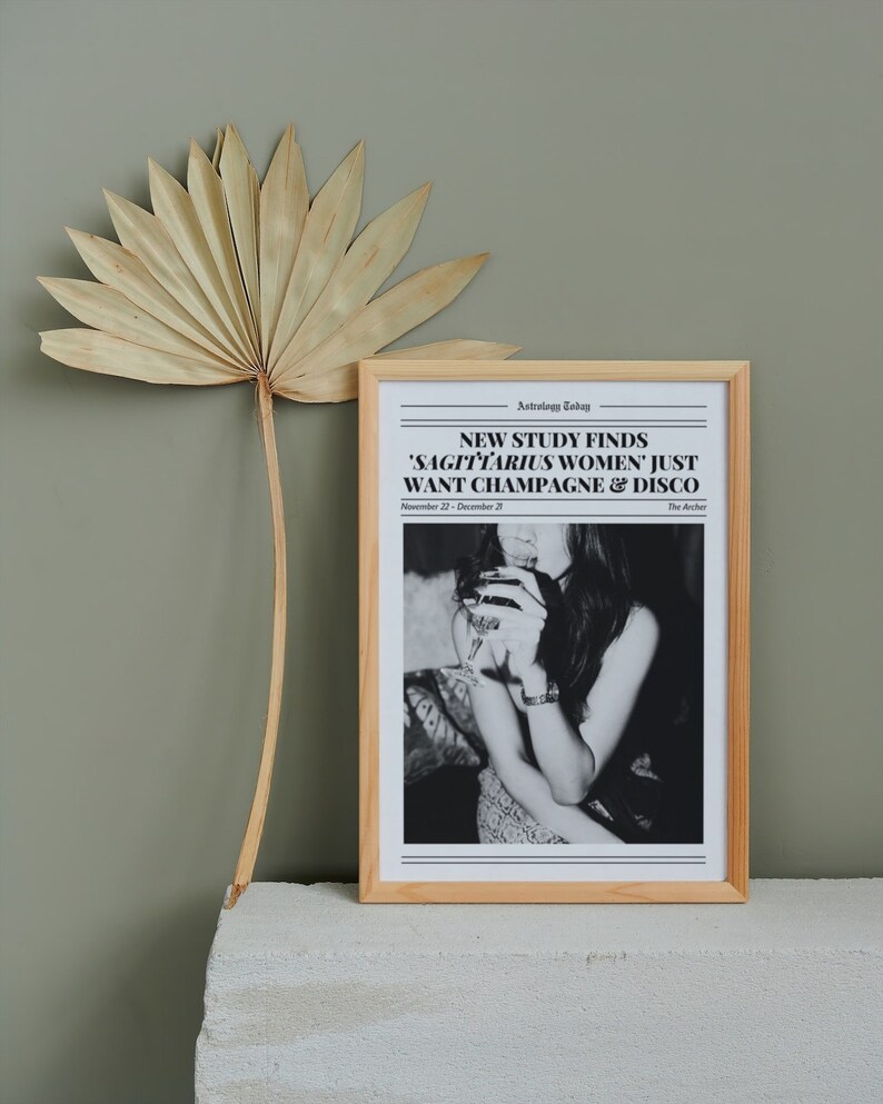 May include: A framed black and white photo of a woman holding a glass of champagne. The photo has a newspaper headline that reads "NEW STUDY FINDS 'SAGITTARIUS WOMEN' JUST WANT CHAMPAGNE & DISCO" with the date "November 22 - December 21" and the text "The Archer".