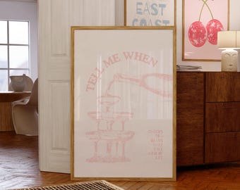 May include: A framed print with the text "TELL ME WHEN" in pink, featuring a champagne tower illustration. Additional framed prints with cherry and cocktail designs are visible. The artwork is displayed in a room with wooden floors.