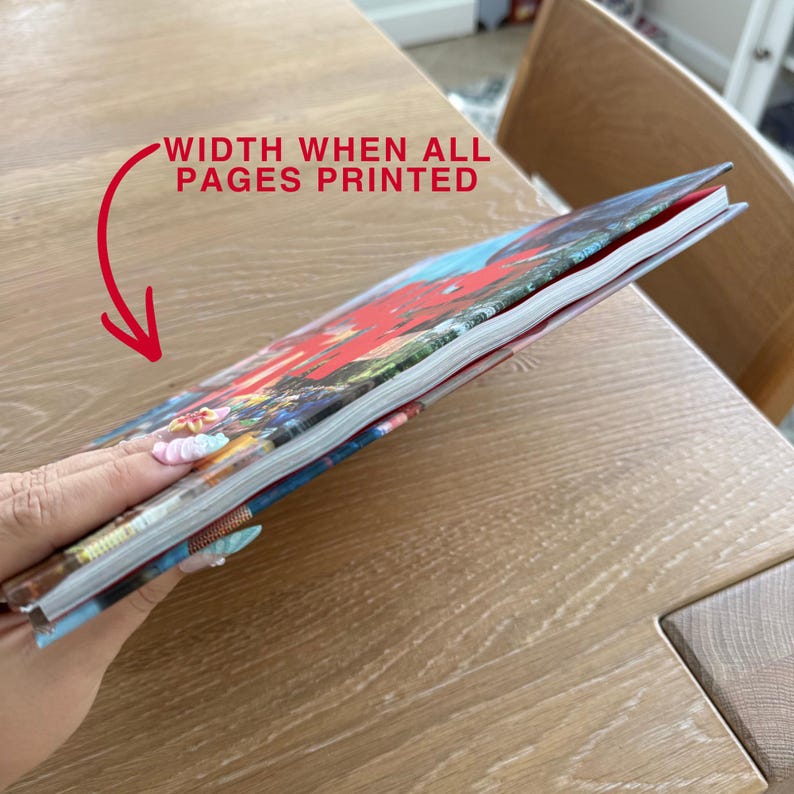 Op de afbeelding: Een dun boek met een kleurrijke omslag met een rood grafisch ontwerp. Een rode pijl wijst naar de zijkant van het boek met de tekst "WIDTH WHEN ALL PAGES PRINTED" in rode hoofdletters, wat de dikte van de ingebonden pagina's aangeeft.