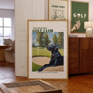 May include: A vintage-style poster with a black Labrador Retriever sitting on a golf course. The poster has the text "The Good Boy Golf Club" and the tagline "Work hard play golf enjoy the sunshine".