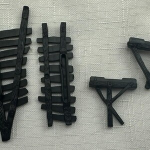 May include: Four black miniature wooden structures, including two fences and two tables. The fences have horizontal slats and vertical supports. The tables have a triangular or rectangular top with angled legs. The items are likely for a model or diorama.