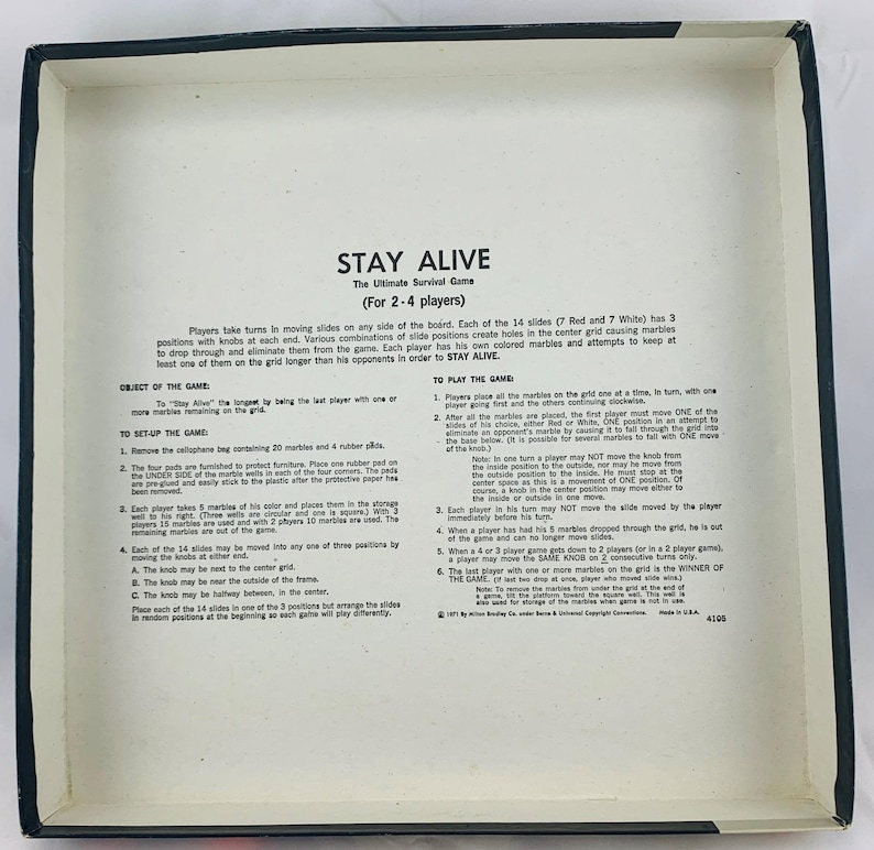 Pode incluir: Um jogo de tabuleiro vintage intitulado "STAY ALIVE" para 2-4 jogadores. O jogo inclui um tabuleiro com 14 slides, bolinhas de gude e bot&otilde;es. O objetivo &eacute; ser o &uacute;ltimo jogador com bolinhas de gude restantes na grade. A caixa do jogo &eacute; branca com texto preto.