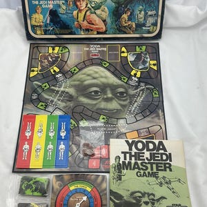 May include: Vintage Star Wars "Yoda The Jedi Master Game" board game. The box features Yoda and Luke Skywalker. The game includes a game board, cards, and other game pieces. The game is from the Star Empire Strikes Back series.