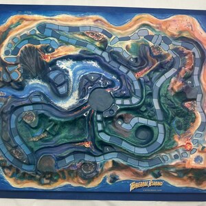 May include: A Fireball Island board game with a detailed island landscape. The game board features a blue ocean, green and brown landmasses, and a winding path. The game's title is visible in the lower right corner.