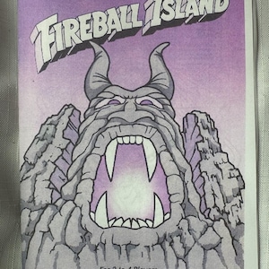 May include: Cover art for the board game Fireball Island. The image features a stylized illustration of a volcanic island with a menacing face, large fangs, and the game's title in bold letters. The text "For 2 to 4 Players" is also visible.